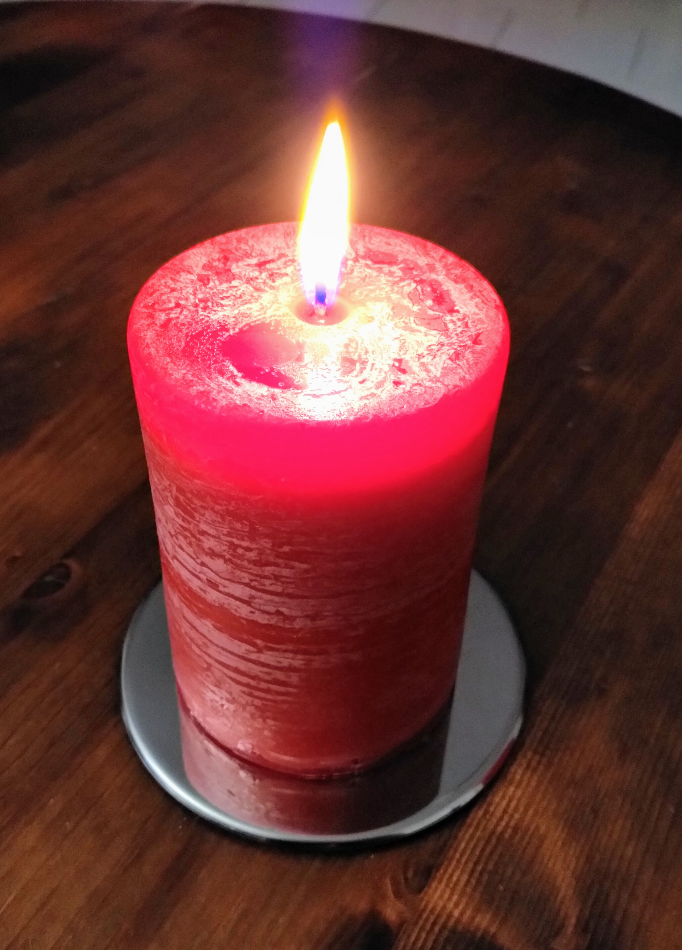 Eine große brennende, rote, Kerze auf einem Tisch